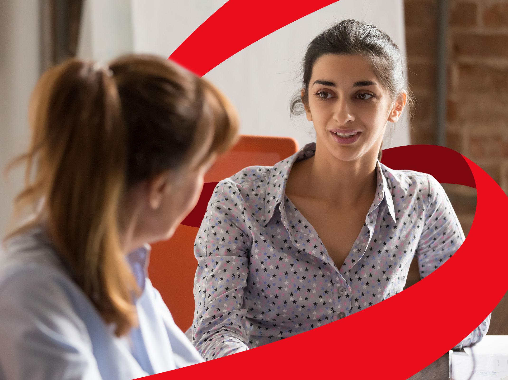 Two female business professionals talking at a conference table in a business setting.